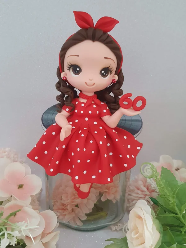 Topo de bolo em biscuit feito pela Teka: mulher de vestido vermelho de bolinhas, para os 60 anos